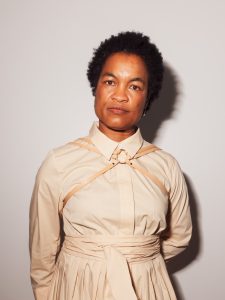 a woman wearing a tan shirt with a we got cookies harness front view